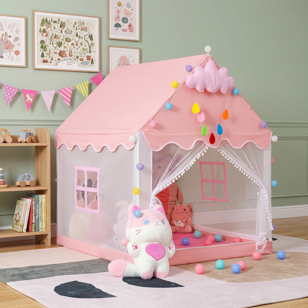 Enchanting pink princess play tent shaped like a house, featuring scalloped white trim, white pom-pom curtains, and heart-shaped side windows, set in a decorated indoor room.