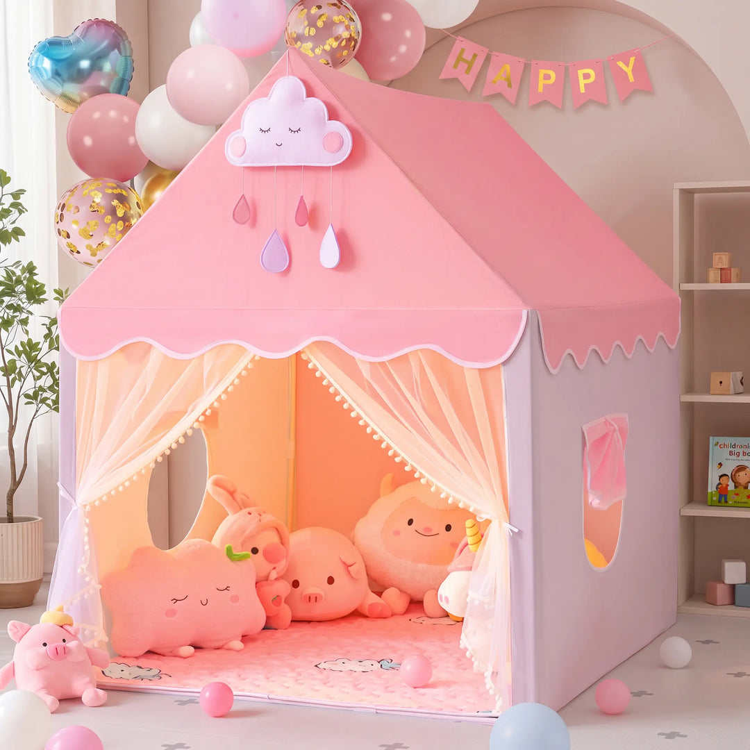 A whimsical pink princess play tent shaped like a house, adorned with scalloped white trim, pom-poms, and mesh curtains, shown in a festive indoor setting with balloons and a &