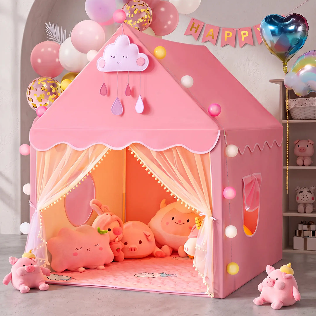 Enchanting pink house-shaped princess play tent set up indoors, featuring scalloped trim with pom-poms, sheer mesh curtains, and a cloud appliqué. Plush toys fill the tent, and balloons decorate the festive background.