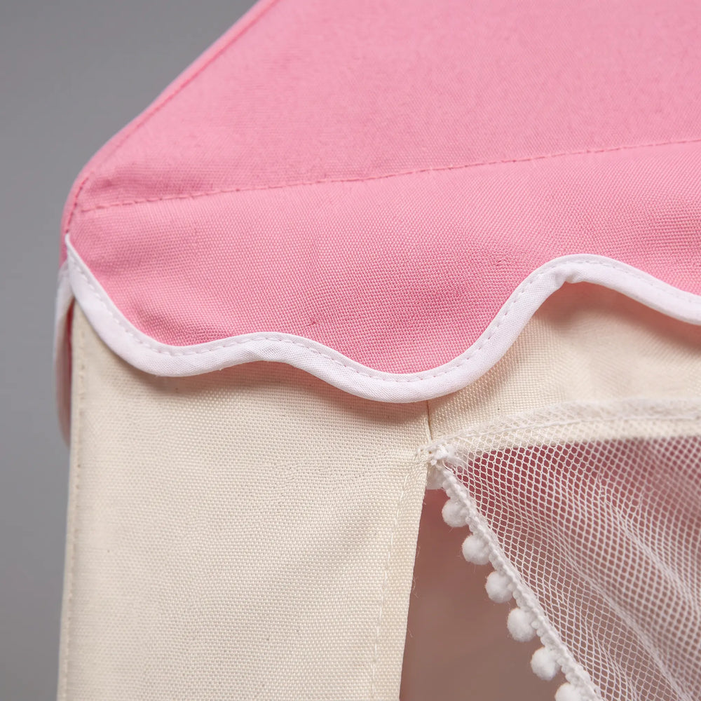 Close-up of a pink play tent roof with white scalloped trim and a light grey fabric tent body, showing a mesh window with white pom-pom trim.
