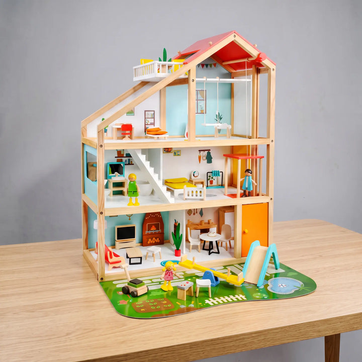 Three-story wooden dollhouse with a pitched red roof, open front revealing detailed rooms with furniture and figures, and an integrated garden play mat with a slide and pond.
